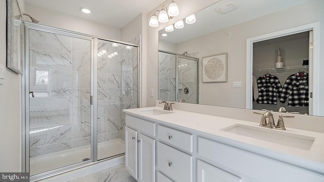 bathroom with a sink, a shower stall, double vanity, and marble finish floor