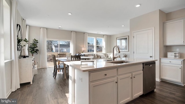 kitchen with dark wood-style flooring, a sink, dishwasher, a kitchen island with sink, and white cabinetry