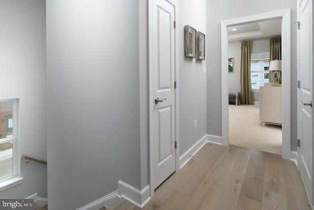 hall with light wood-type flooring, baseboards, and an upstairs landing