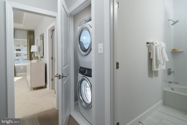 laundry area featuring baseboards, laundry area, and stacked washer / drying machine