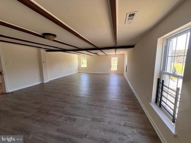 empty room featuring baseboards, beamed ceiling, dark wood finished floors, and visible vents