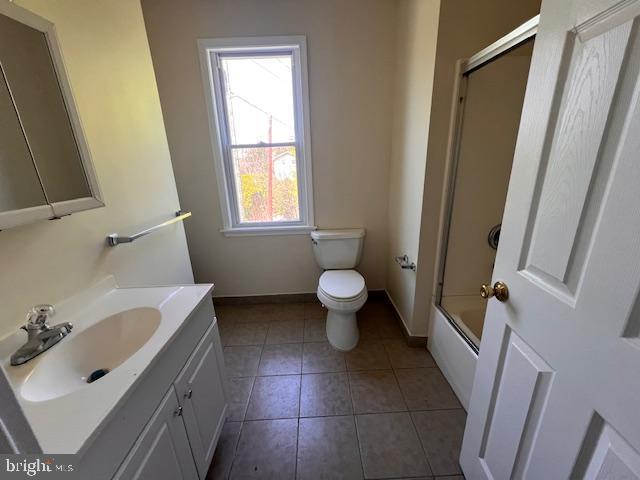 full bathroom with shower / bath combination with glass door, vanity, toilet, tile patterned floors, and baseboards