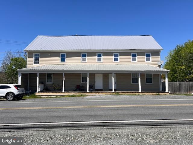 view of front of home featuring covered porch, fence, and metal roof