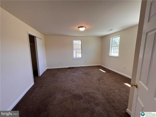 unfurnished bedroom with baseboards, dark carpet, and visible vents