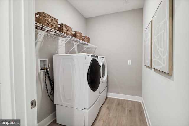 clothes washing area featuring laundry area, washer and clothes dryer, light wood-style flooring, and baseboards