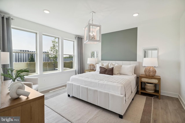 bedroom featuring recessed lighting, baseboards, an inviting chandelier, and wood finished floors