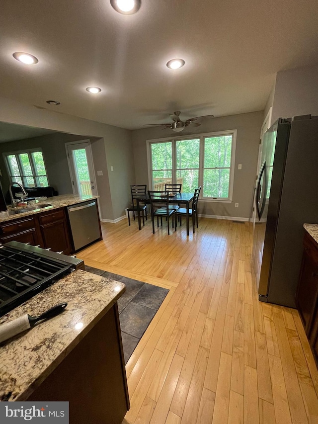 kitchen with a sink, baseboards, ceiling fan, and stainless steel appliances