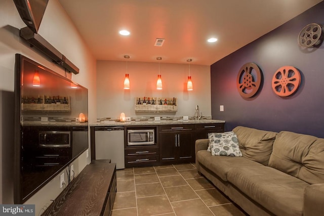 bar with visible vents, dishwashing machine, dark tile patterned floors, stainless steel microwave, and wet bar