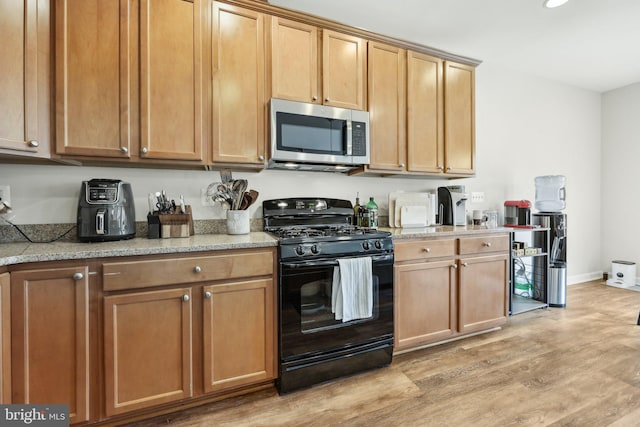 207 Community Center Ave Unit 207, Gaithersburg, MD 20878 - kitchen with baseboards, black range with gas stovetop, light wood-type flooring, recessed lighting, and stainless steel microwave
