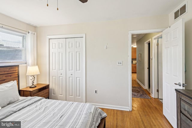 bedroom with visible vents, a closet, baseboards, ceiling fan, and light wood finished floors