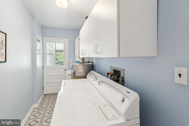 washroom featuring baseboards, washer and clothes dryer, cabinet space, and water heater