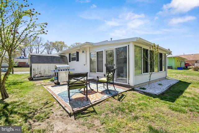 back of property with a patio, a shed, a sunroom, an outbuilding, and a yard