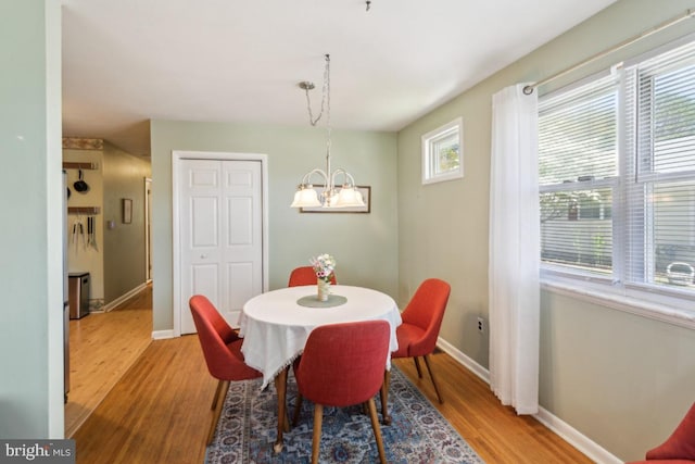 dining area featuring baseboards, wood finished floors, and a notable chandelier
