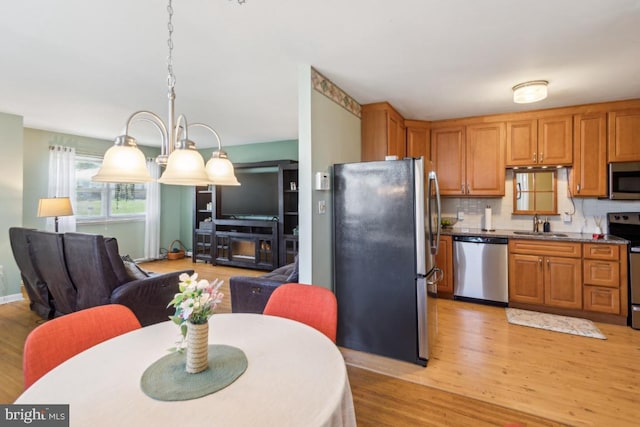kitchen with a sink, decorative backsplash, stainless steel appliances, and light wood-style flooring