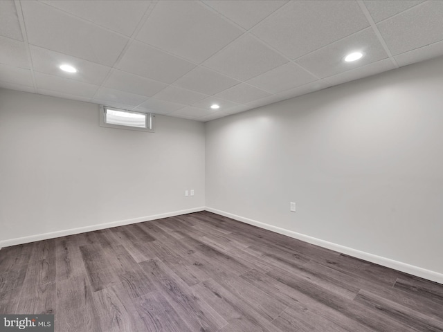 basement featuring recessed lighting, baseboards, dark wood finished floors, and a paneled ceiling