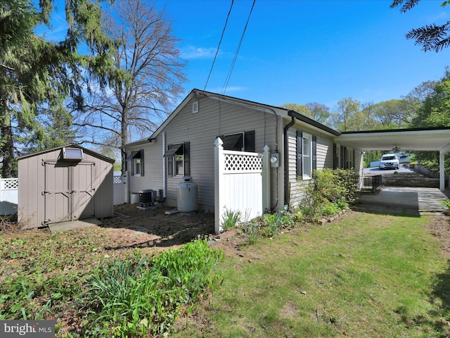 view of side of property featuring an outdoor structure, fence, an attached carport, a lawn, and a storage shed