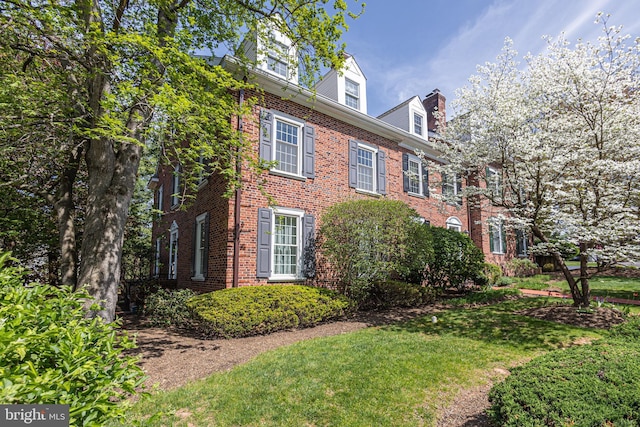 view of side of property featuring brick siding and a yard