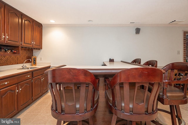 bar with a sink, decorative backsplash, crown molding, and recessed lighting