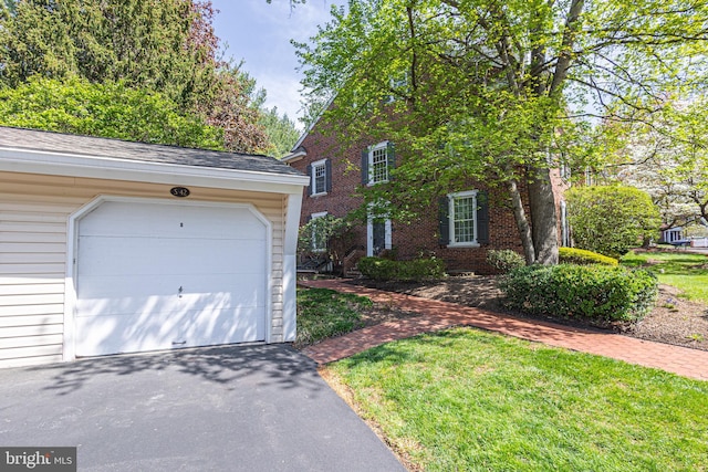 view of front facade with driveway, a front lawn, and brick siding