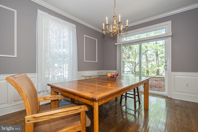 dining area featuring ornamental molding, wainscoting, a decorative wall, dark wood-style floors, and a chandelier