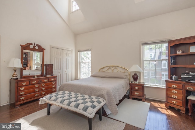 bedroom featuring visible vents, a skylight, high vaulted ceiling, a closet, and dark wood-type flooring