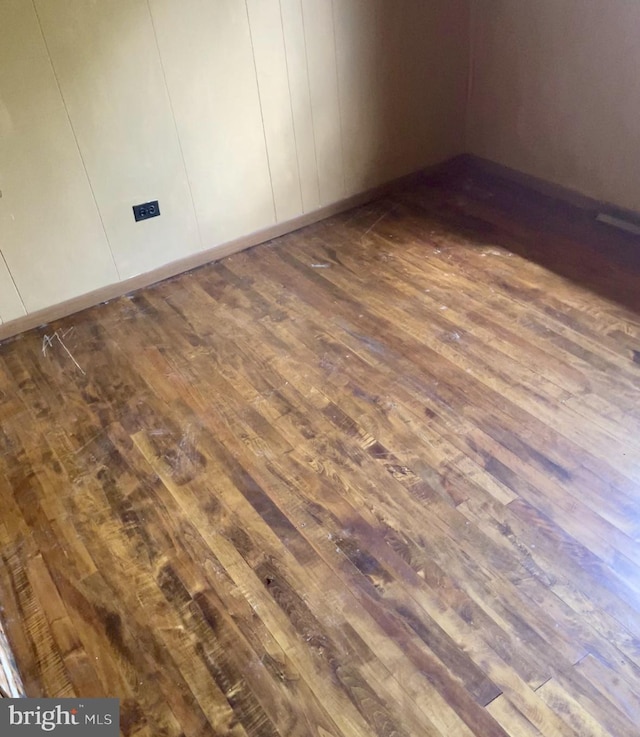 spare room featuring baseboards and dark wood-style floors