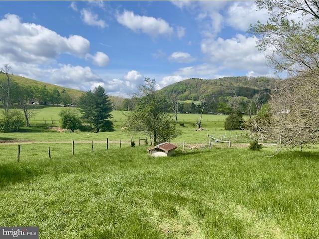 view of yard featuring a mountain view, a rural view, and fence