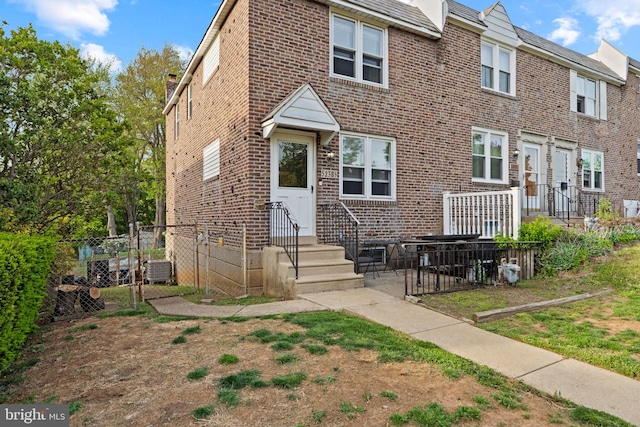 rear view of house featuring brick siding, fence, central AC unit, and a patio area