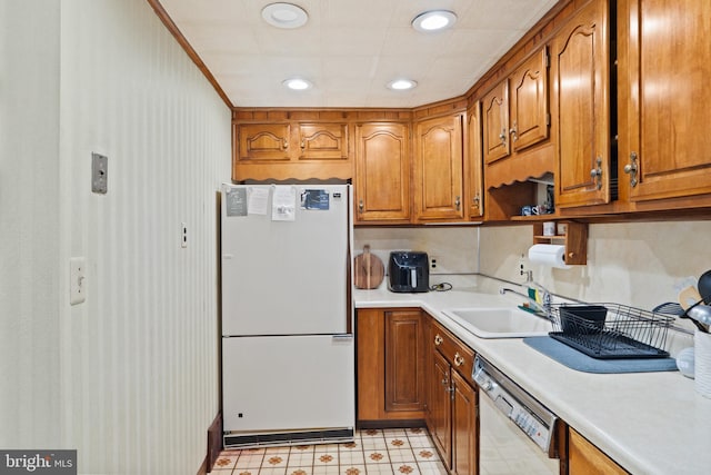 kitchen featuring white appliances, recessed lighting, light countertops, brown cabinets, and a sink