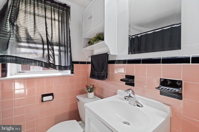 full bathroom with toilet, tile walls, a wealth of natural light, and vanity
