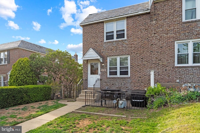 townhome / multi-family property with brick siding, a front lawn, and a high end roof
