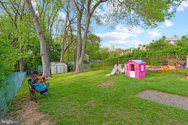view of yard with a storage shed, an outdoor structure, a playground, and a fenced backyard
