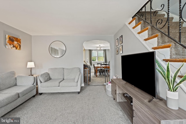 carpeted living room with stairway and arched walkways