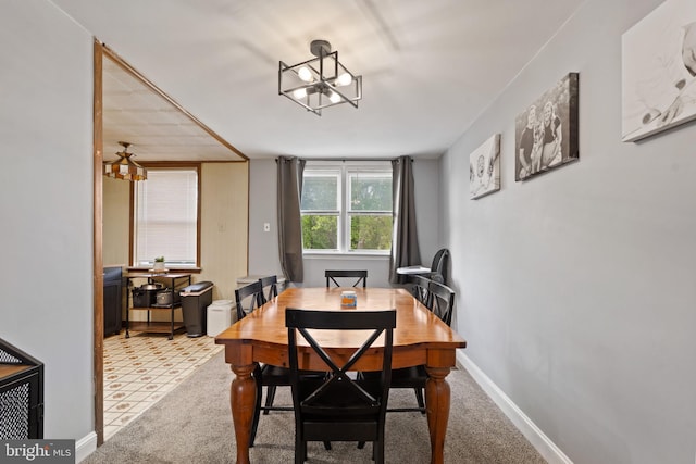 carpeted dining space featuring an inviting chandelier and baseboards