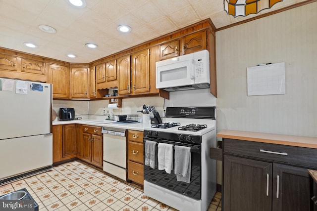 kitchen with white appliances, recessed lighting, brown cabinetry, and light countertops