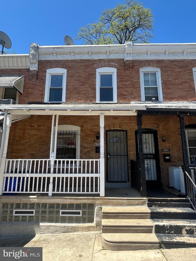 view of front of home featuring brick siding and covered porch