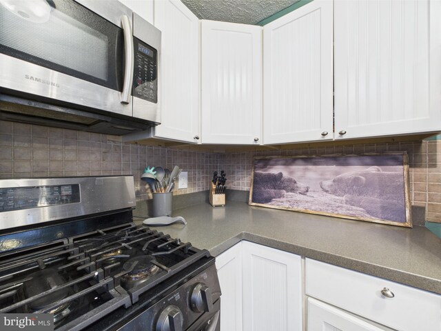 4105 Wilcox Ct, Pocono Lake, PA 18347 - kitchen with white cabinetry, decorative backsplash, dark countertops, and appliances with stainless steel finishes