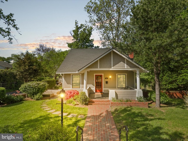 view of front of house with fence, a chimney, a porch, and a front yard