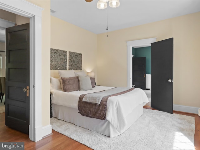 bedroom with baseboards, wood finished floors, and radiator