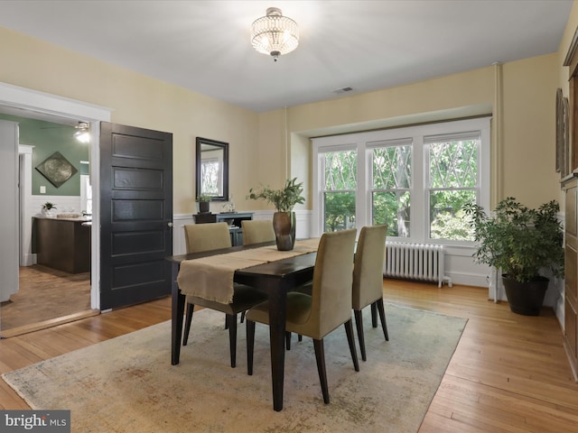 dining area with visible vents, radiator heating unit, and light wood-type flooring