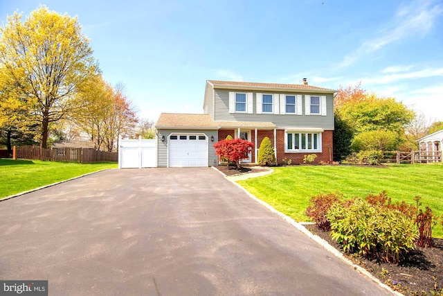 traditional-style home featuring fence, an attached garage, a front lawn, and aphalt driveway