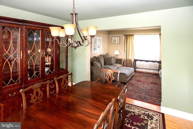 dining space featuring an inviting chandelier, baseboards, and wood finished floors