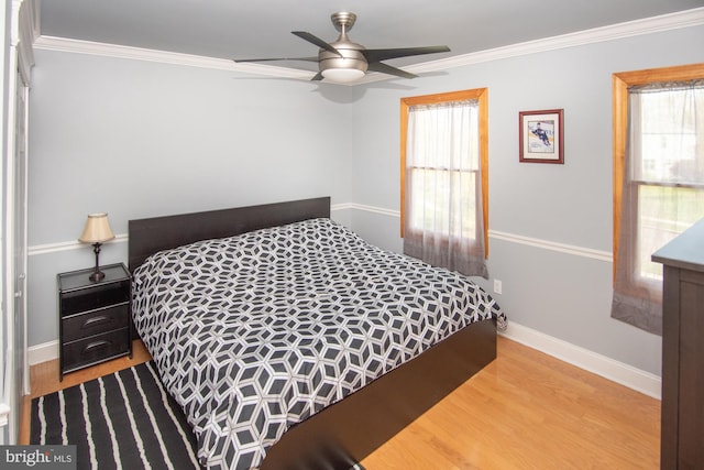 bedroom featuring baseboards, ornamental molding, multiple windows, and wood finished floors