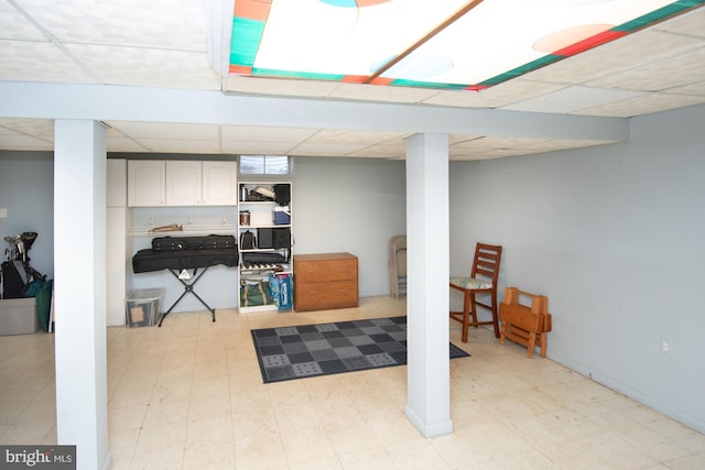 finished below grade area with a paneled ceiling and light floors