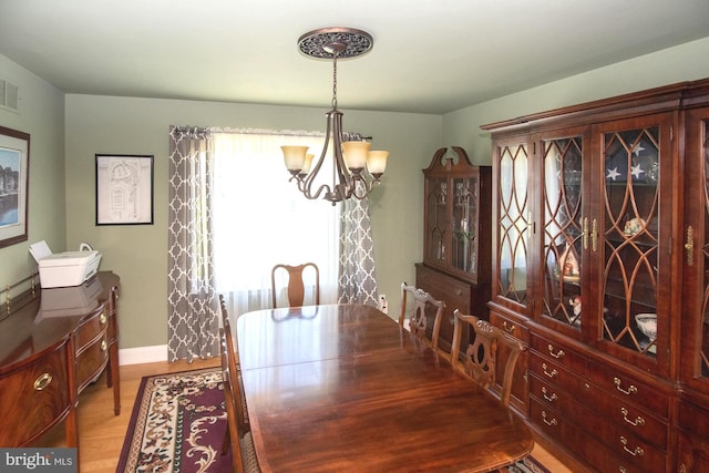 dining space with baseboards, wood finished floors, a notable chandelier, and visible vents
