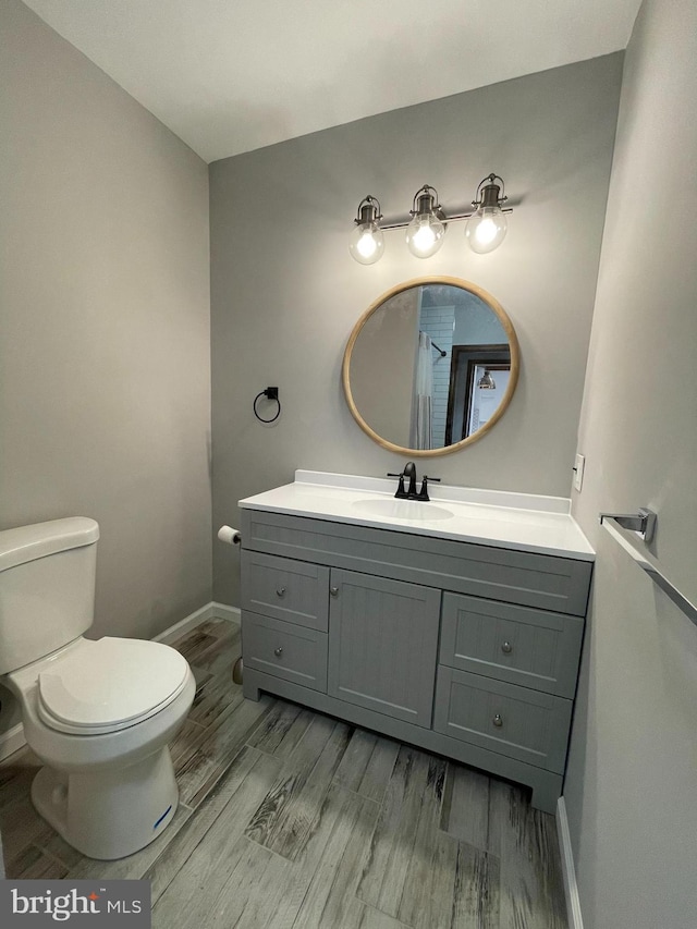 bathroom featuring vanity, baseboards, toilet, and wood finished floors