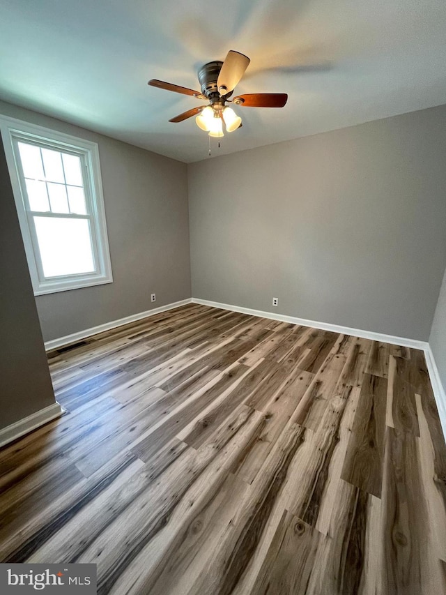 empty room featuring baseboards, a ceiling fan, and wood finished floors