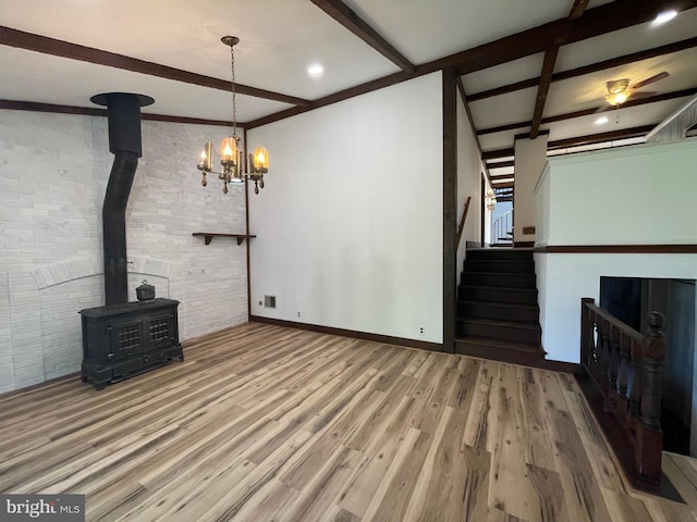 unfurnished living room featuring brick wall, beam ceiling, a wood stove, and wood finished floors