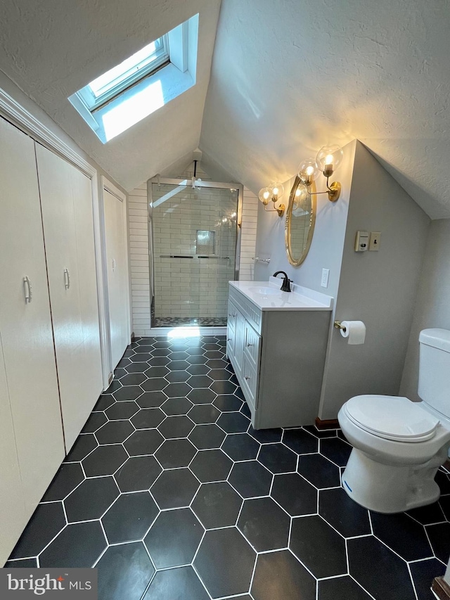 full bath with vanity, toilet, lofted ceiling with skylight, a ceiling fan, and a stall shower