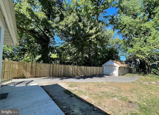view of yard featuring a detached garage, fence, an outbuilding, and a patio area